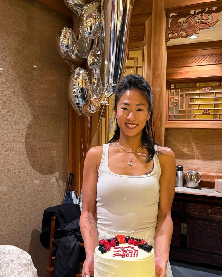 Samantha holding a cake with balloons behind her