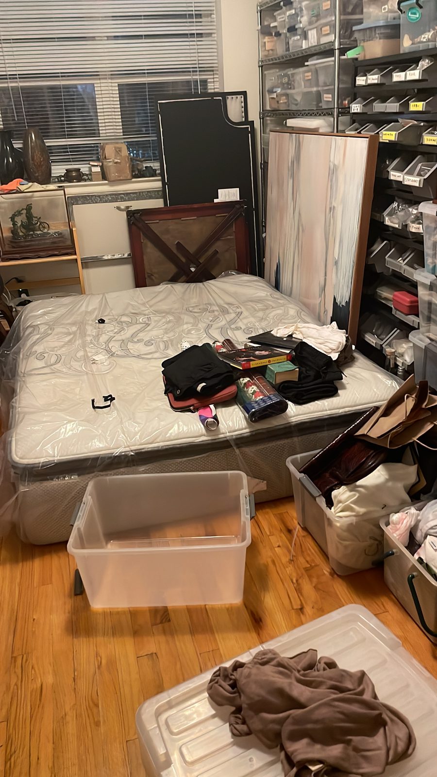 A mattress on the floor with clothes and boxes